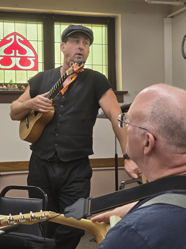 Lil' Rev explaining bluegrass ukulele techniques to workshop participants